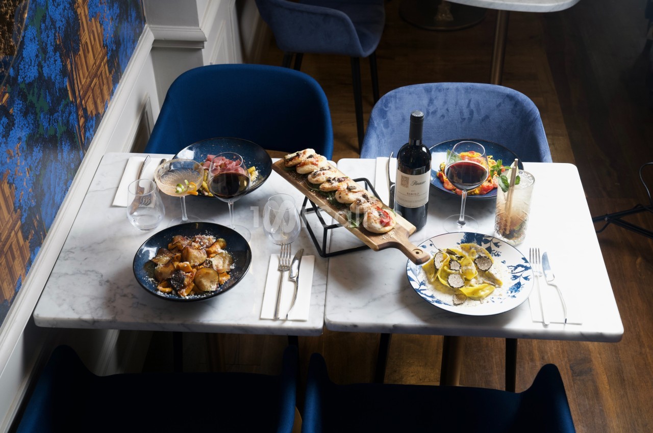 Table dressée avec des plats variés, dont des fruits de mer, des viandes, un plateau de brochettes, et des verres de vin.