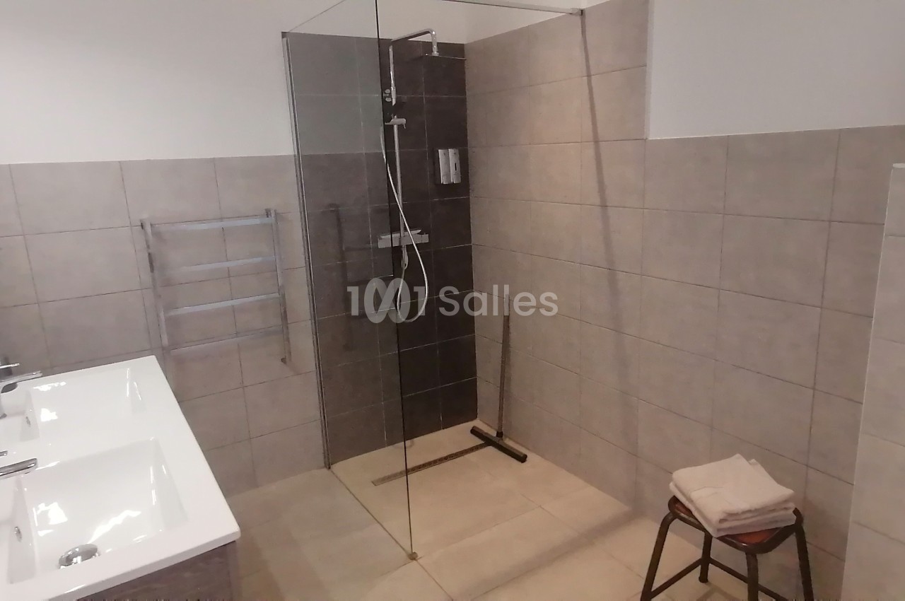 Salle de bain moderne avec douche à l'italienne, lavabo double, carrelage beige et accessoires minimalistes.