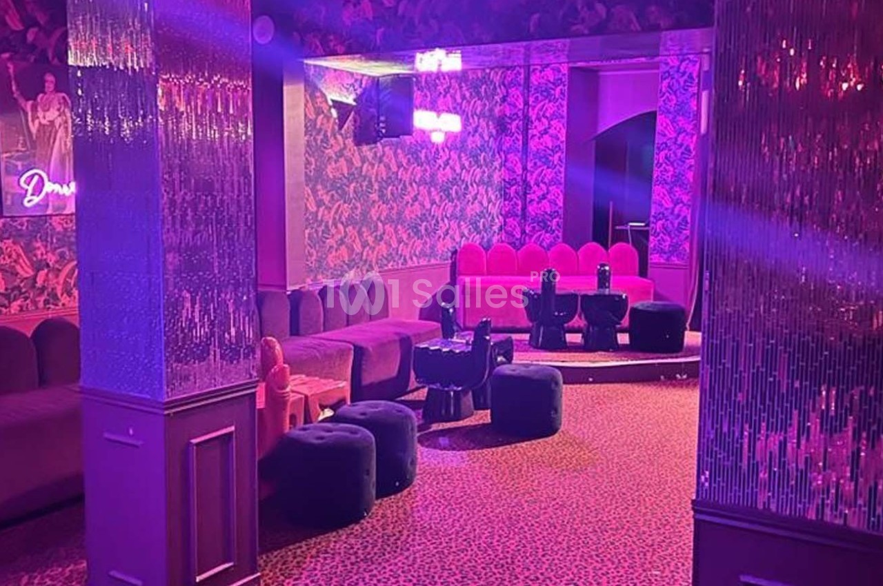 Salle de réception avec banquettes roses, tabourets noirs et éclairage tamisé aux tons violets.
