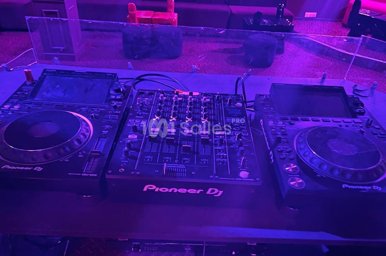 Table de mixage Pioneer DJ avec deux platines et un contrôleur audio dans un environnement faiblement éclairé.