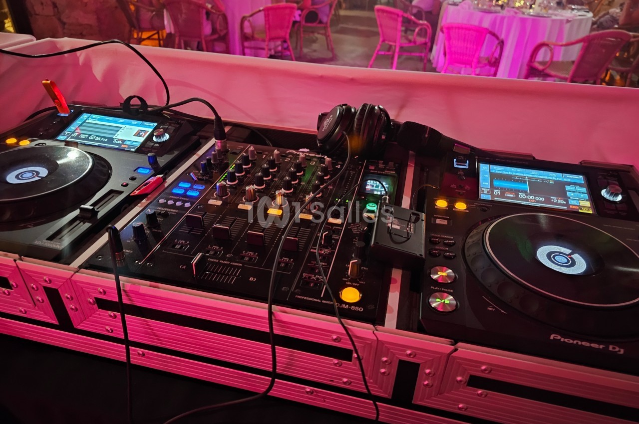 Deux platines DJ et une table de mixage avec des casques, installées dans un espace de réception éclairé.