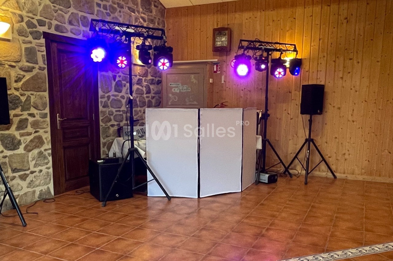 Installation de matériel de sonorisation et éclairage coloré dans une salle aux murs en pierre et bois.