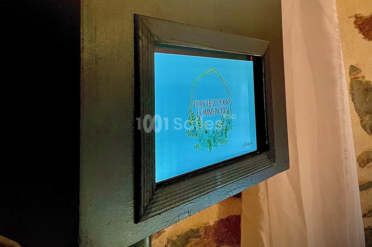 Écran tactile encastré affichant un message ’Touchez pour commencer’ avec un design floral sur fond bleu.