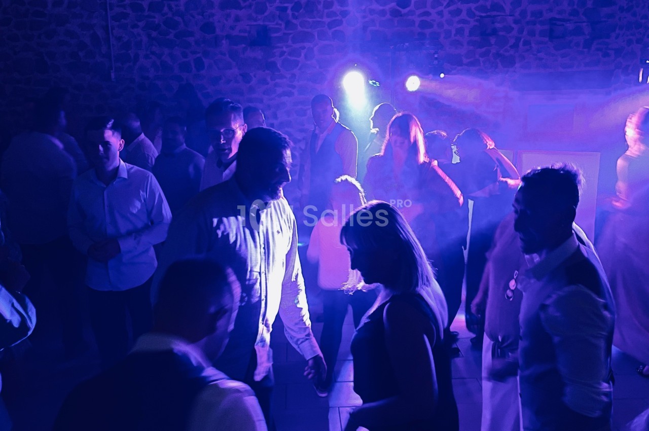 Personnes dansant dans une salle sombre éclairée par des lumières bleues et violettes, ambiance festive.