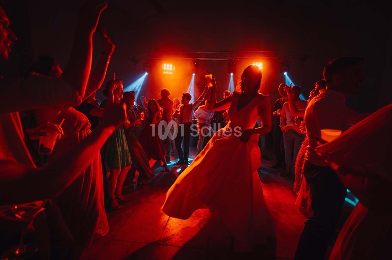 Personnes dansant dans une ambiance festive avec éclairage rouge et bleu sur une piste de danse.