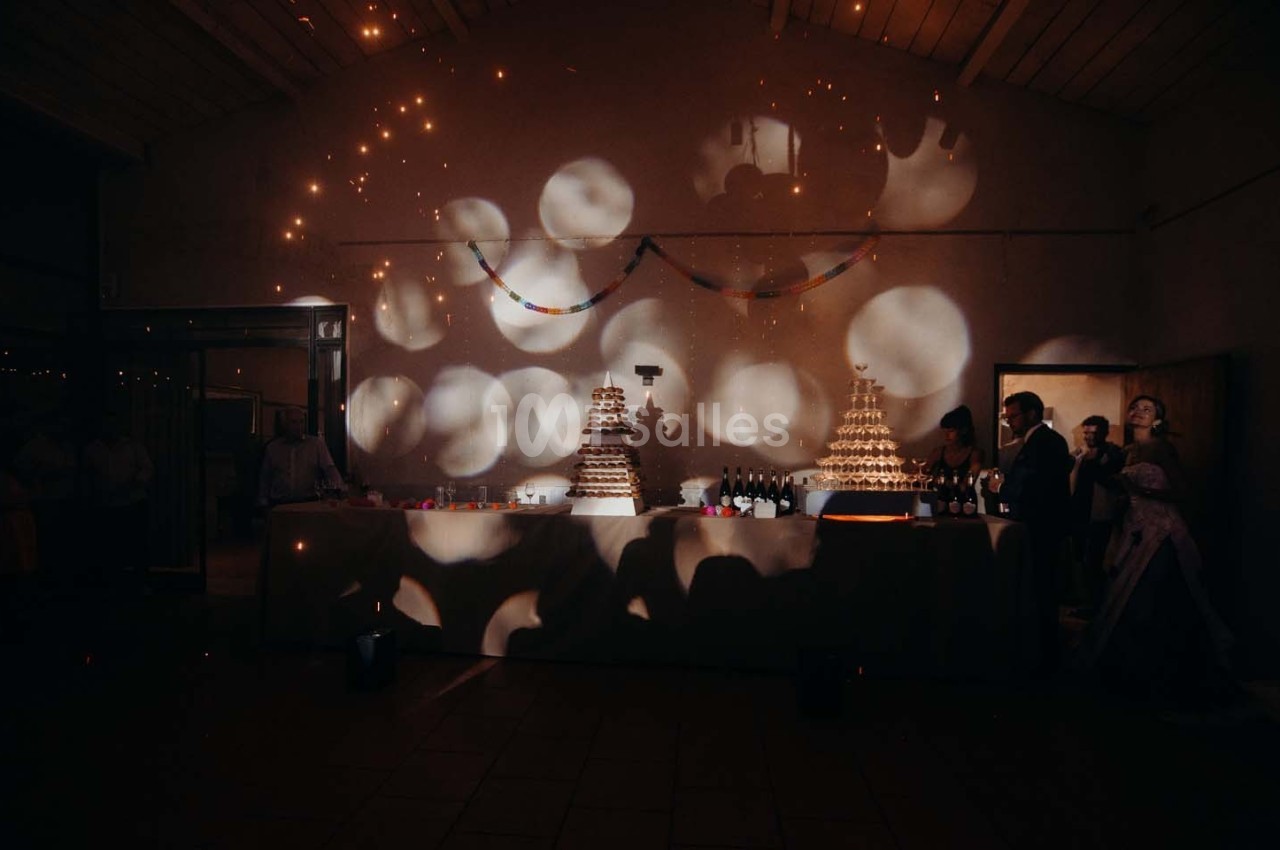 Table décorée avec des pyramides de choux et des bouteilles, éclairée par des lumières tamisées dans une salle sombre.