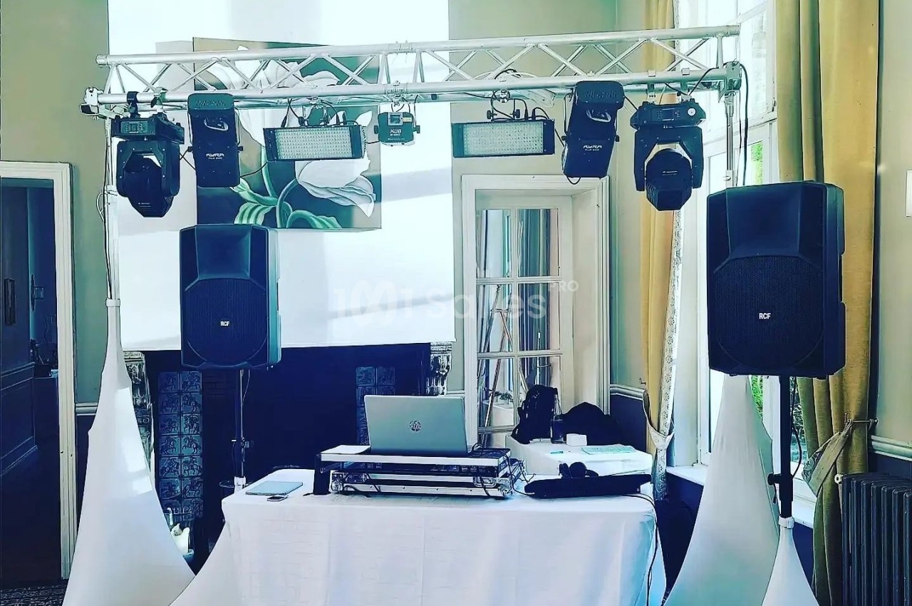 Installation de matériel de sonorisation et d'éclairage avec une table de mixage dans une salle lumineuse.