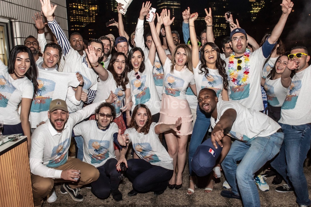 Groupe de personnes souriantes posant ensemble lors d'un événement festif en plein air, portant des t-shirts assortis.