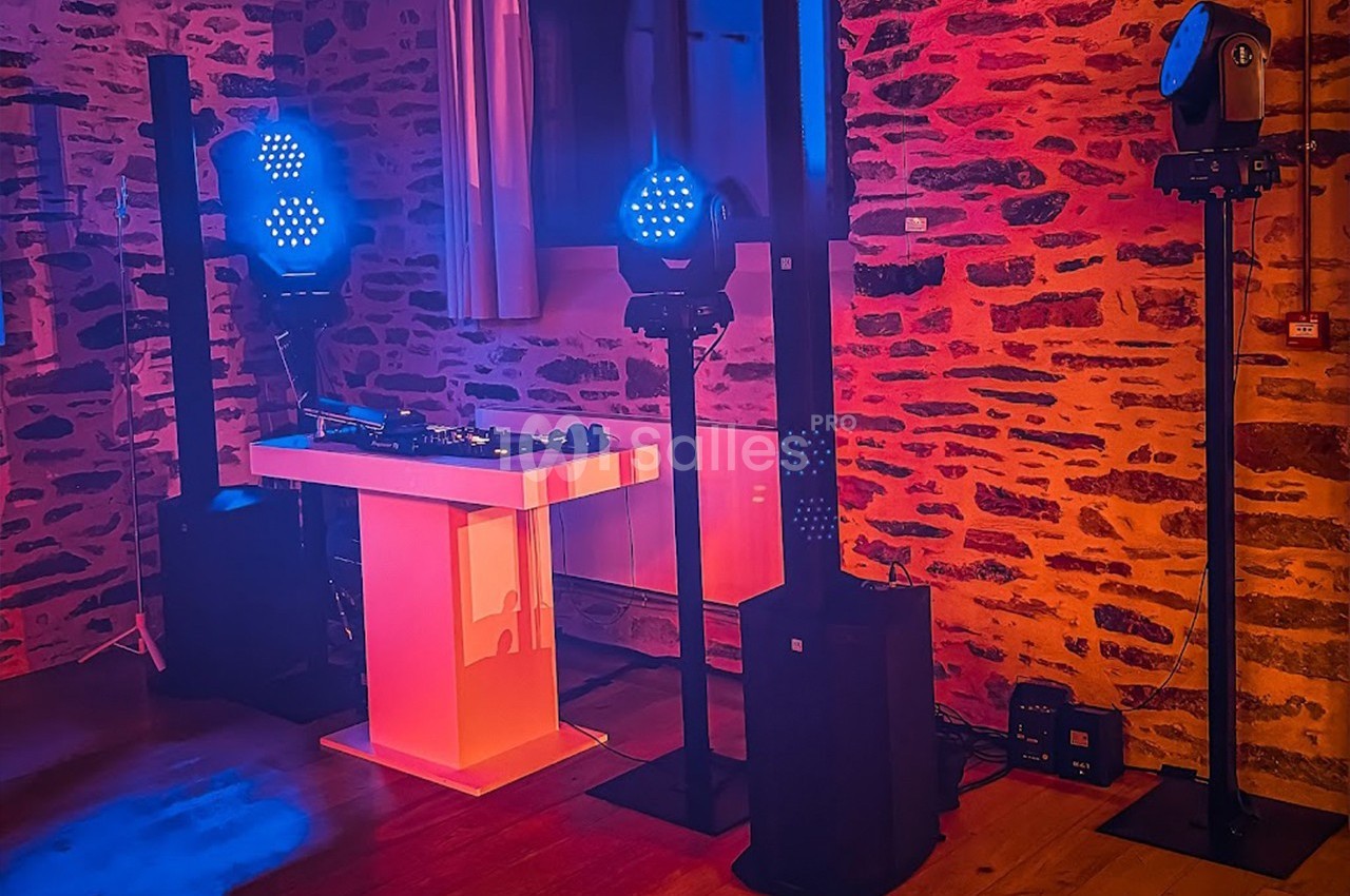 Installation de matériel de sonorisation et éclairage avec projecteurs LED bleus dans une salle aux murs en pierre.