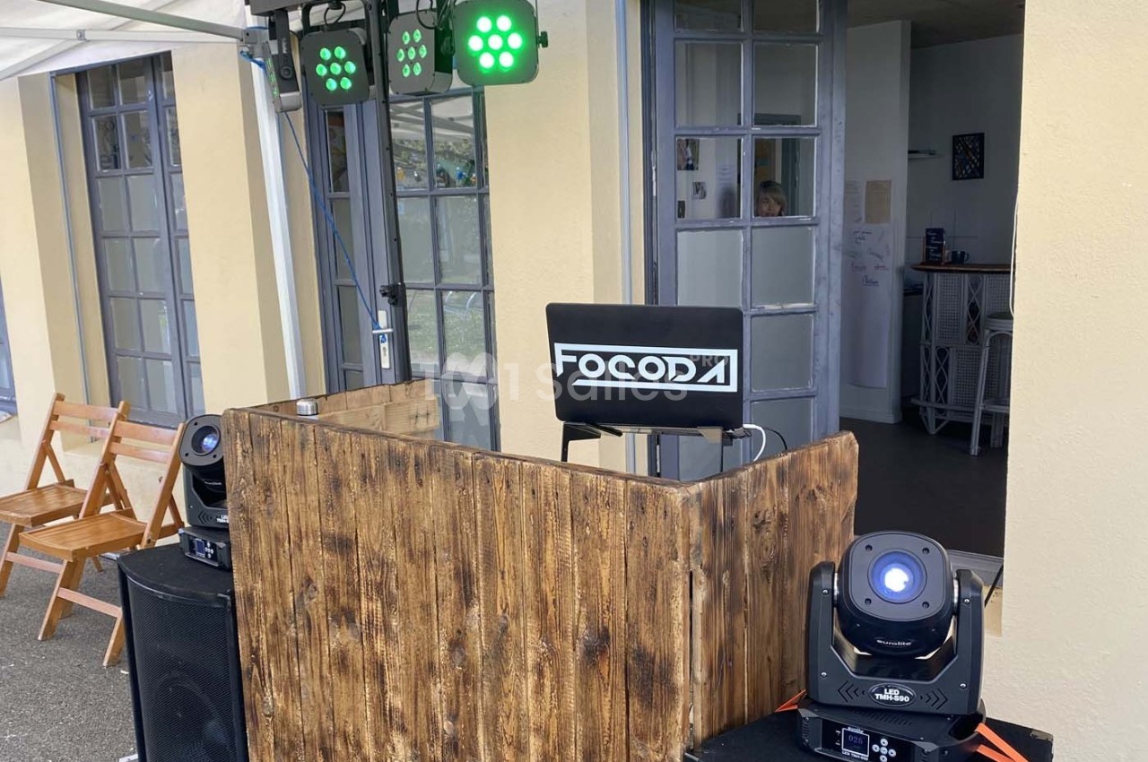 Installation de matériel de sonorisation et d'éclairage avec une table en bois et des projecteurs LED.