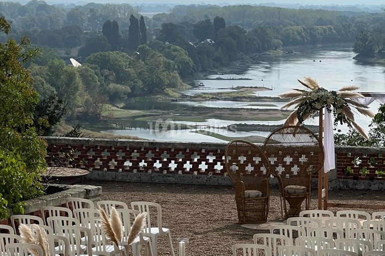 Chaises blanches disposées en extérieur face à une vue panoramique sur une rivière et un paysage verdoyant.