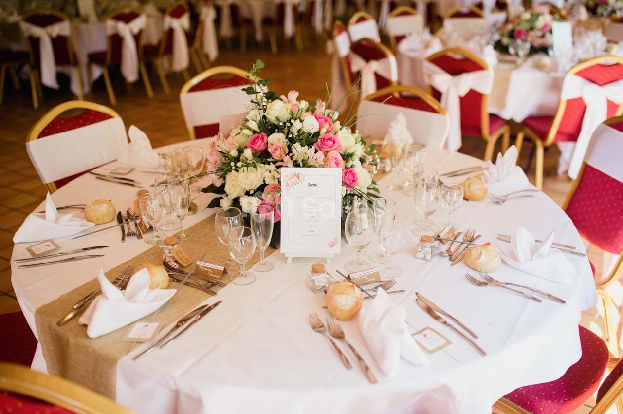 Table de réception élégamment dressée avec une nappe blanche, un centre de table floral et des couverts disposés avec soin.