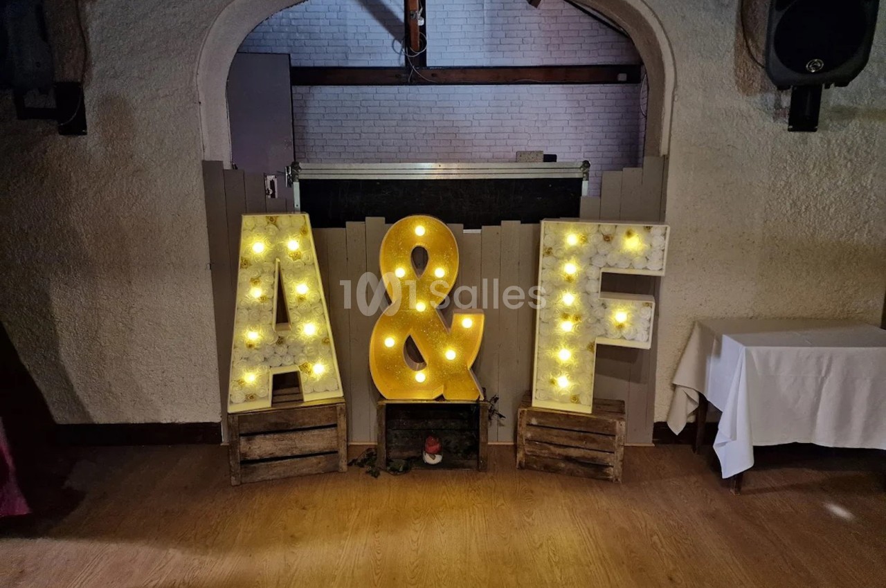 Lettres lumineuses ’A’ et ’F’ avec une esperluette, posées sur des caisses en bois devant un mur clair.