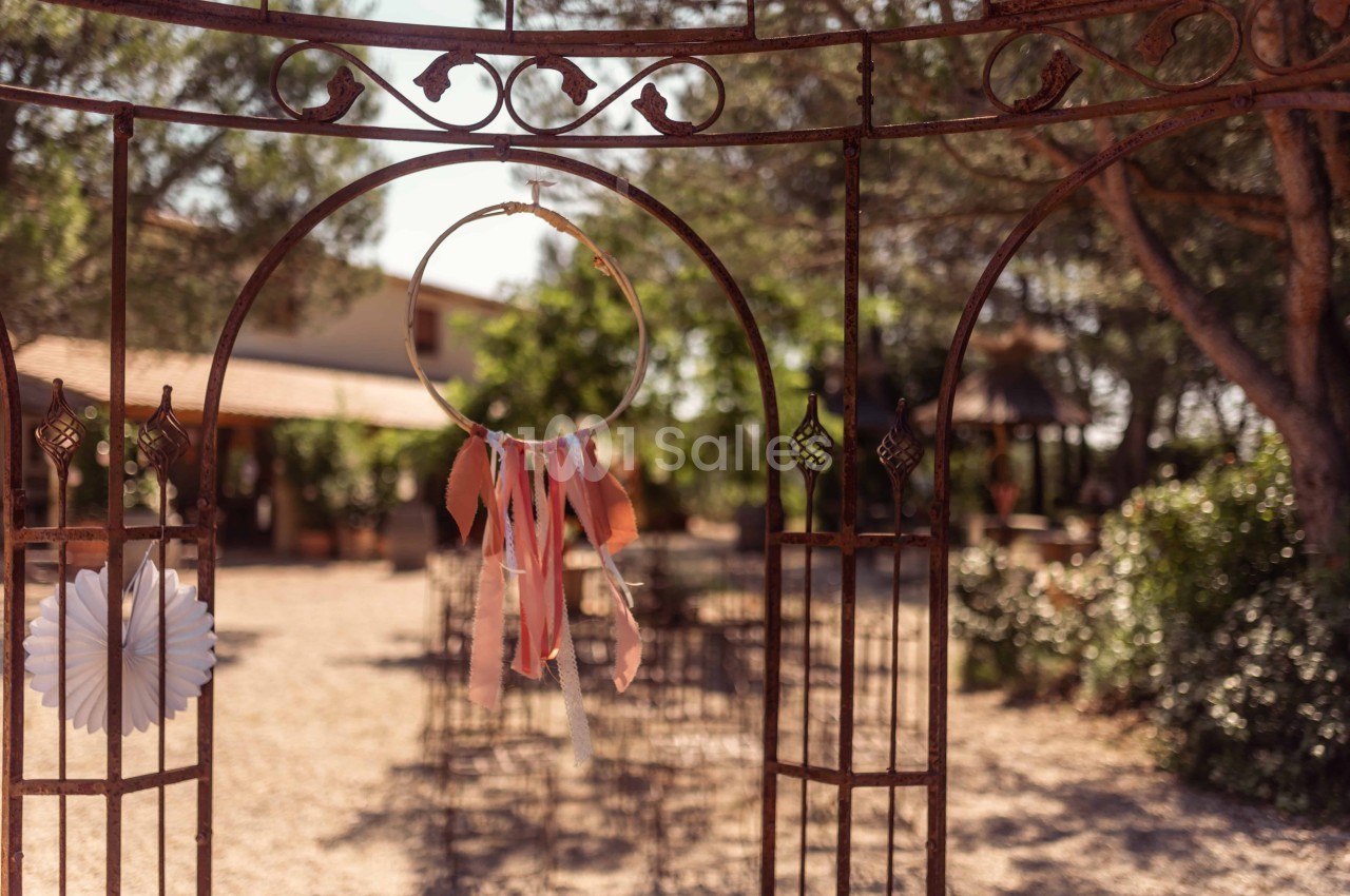 Attrait métallique décoré avec un attrape-rêves coloré, donnant sur un jardin ensoleillé avec des chaises disposées.