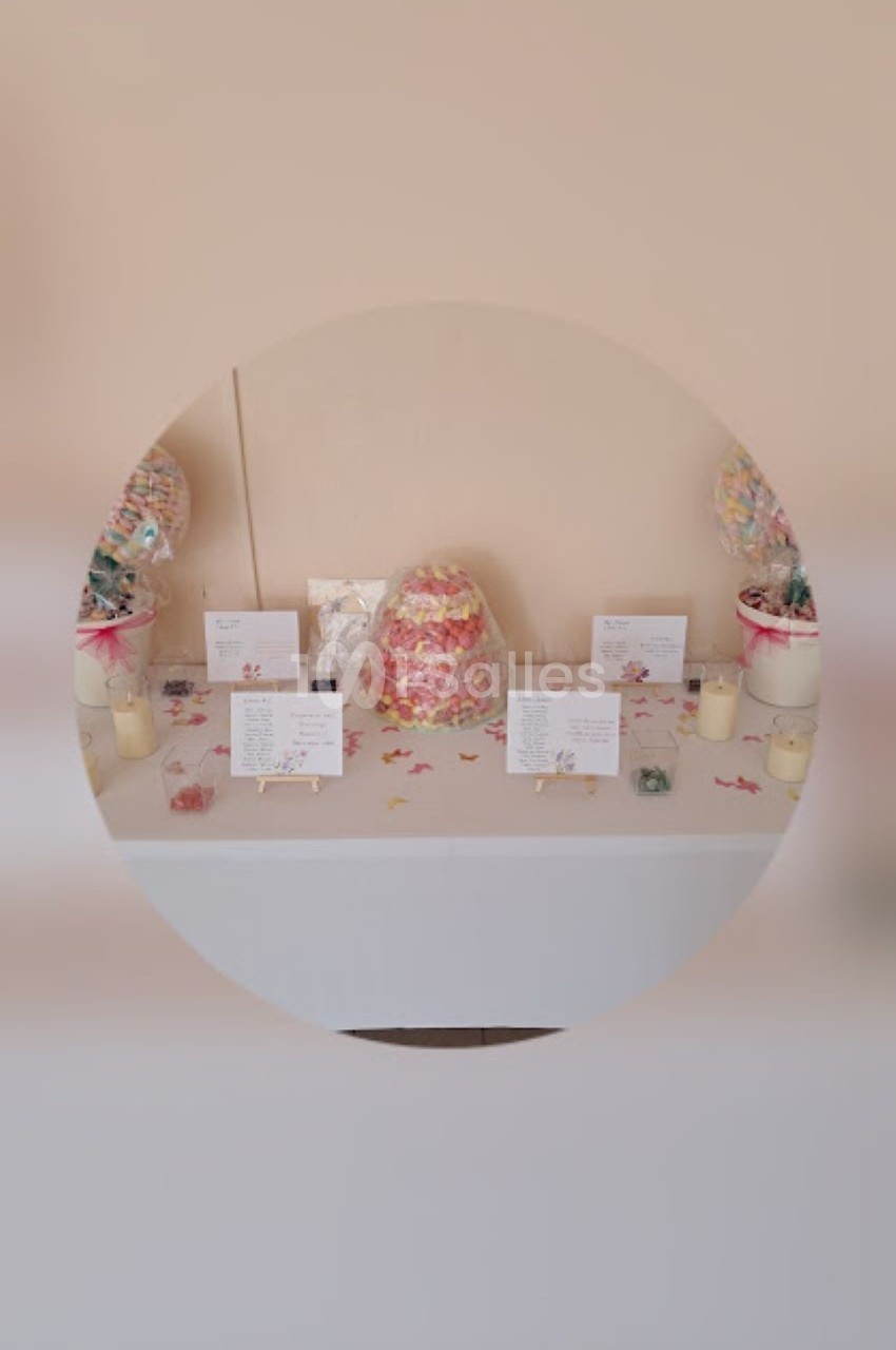Table décorée avec des bonbonnières, des cartes et des bougies, sur fond beige.