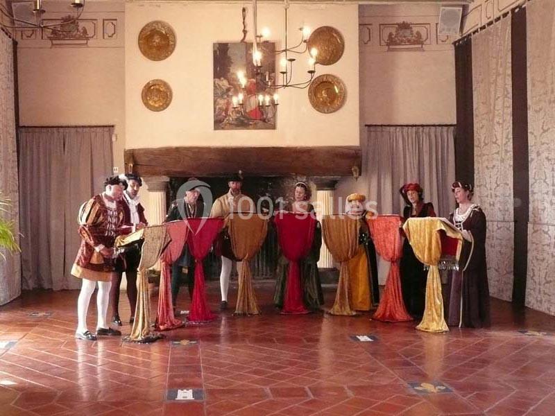 Un groupe de personnes en costumes d'époque chante autour de lutrins dans une salle décorée de style ancien.