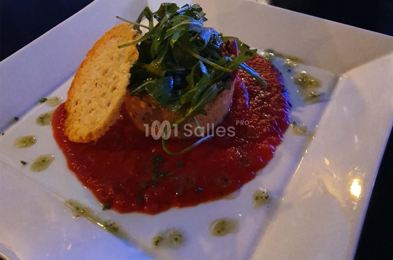 Plat raffiné composé d'une mousse sur coulis de tomate, garni de roquette et d'une tuile croustillante.