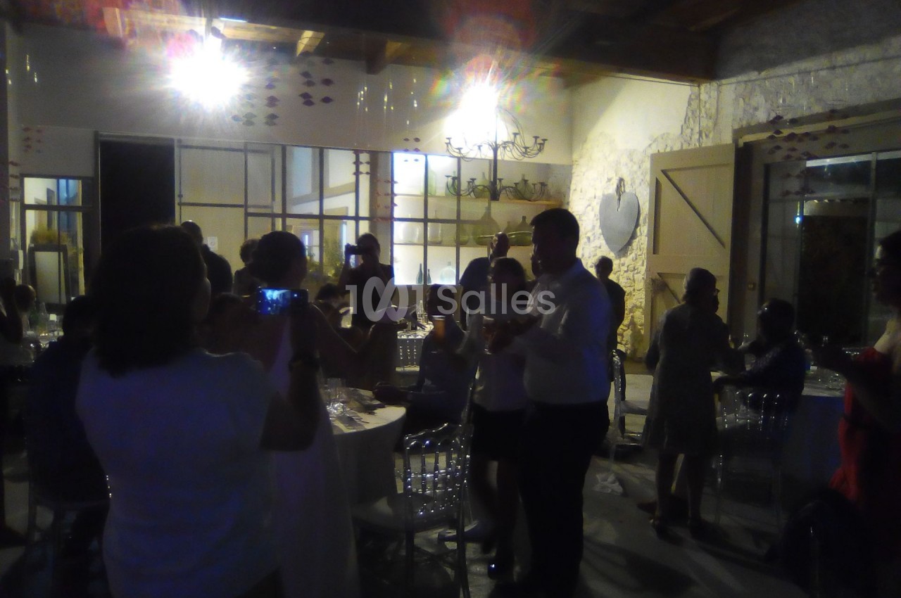 Des personnes rassemblées dans une salle faiblement éclairée, discutant et prenant des photos lors d'un événement.