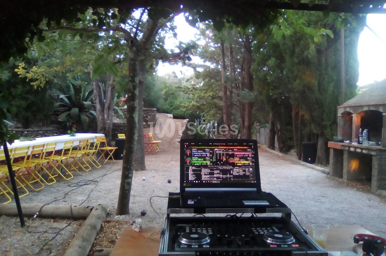 Ordinateur portable avec logiciel de mixage installé, posé sur une table en extérieur près d'une allée bordée d'arbres.