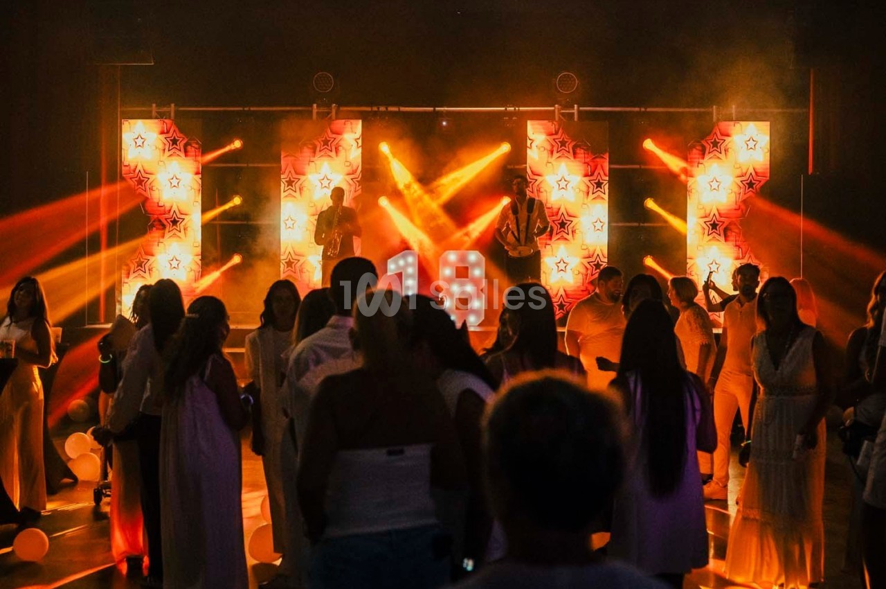 Groupe de personnes dansant lors d'une fête avec éclairages colorés et décorations lumineuses en arrière-plan.
