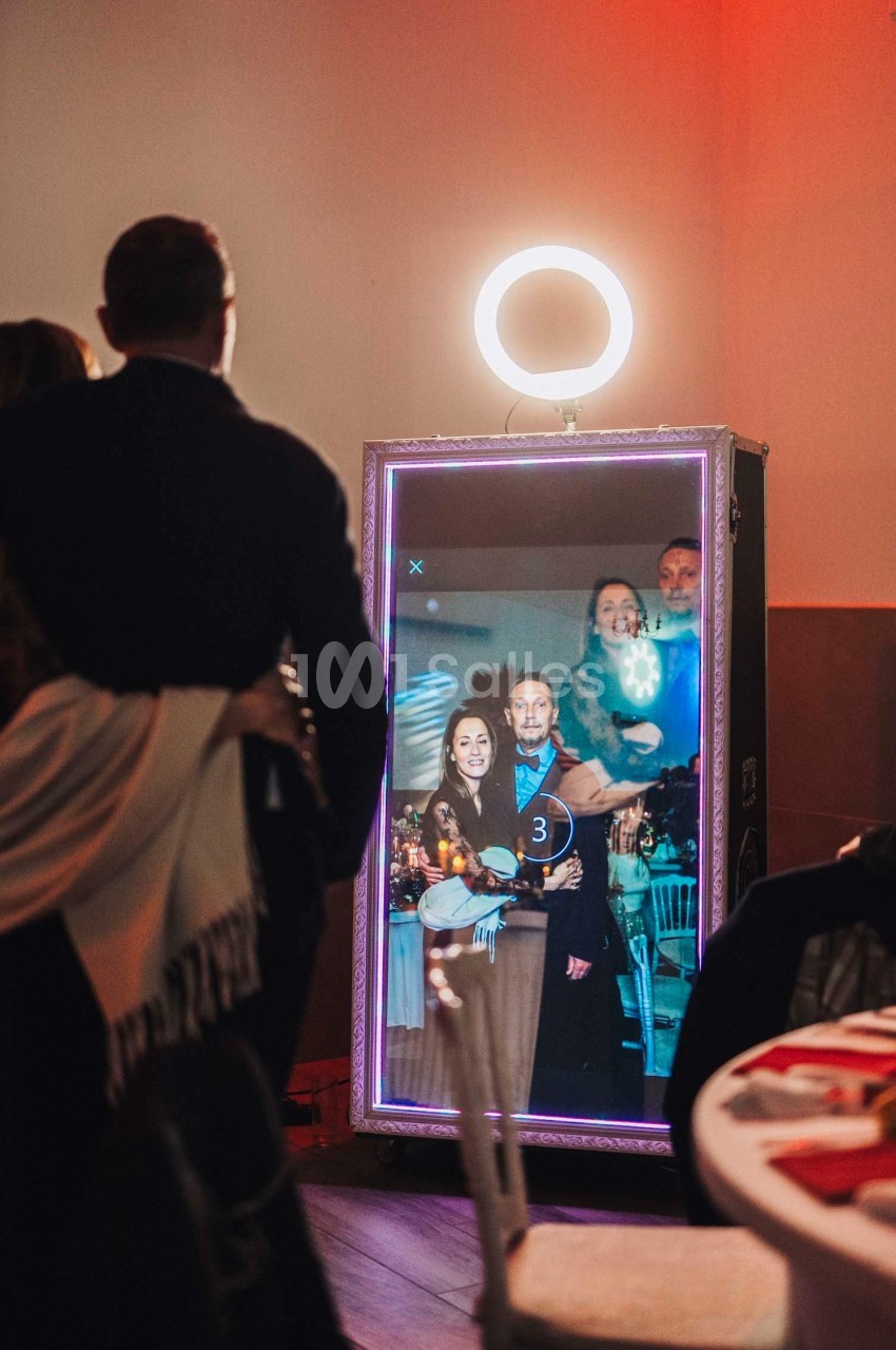 Un groupe de personnes se prend en photo devant un miroir interactif éclairé par une lampe circulaire.