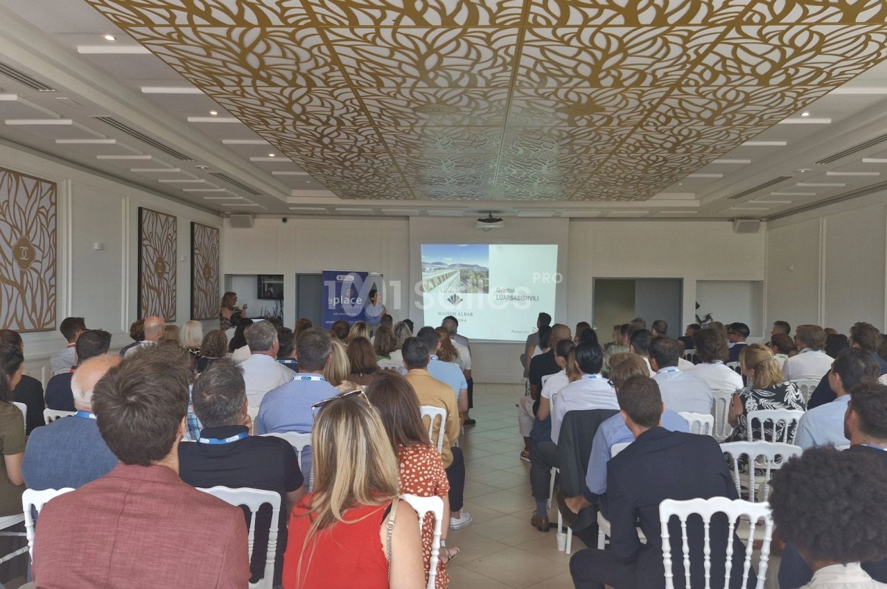 Salle de conférence avec des participants assis, regardant une présentation projetée sur un écran.