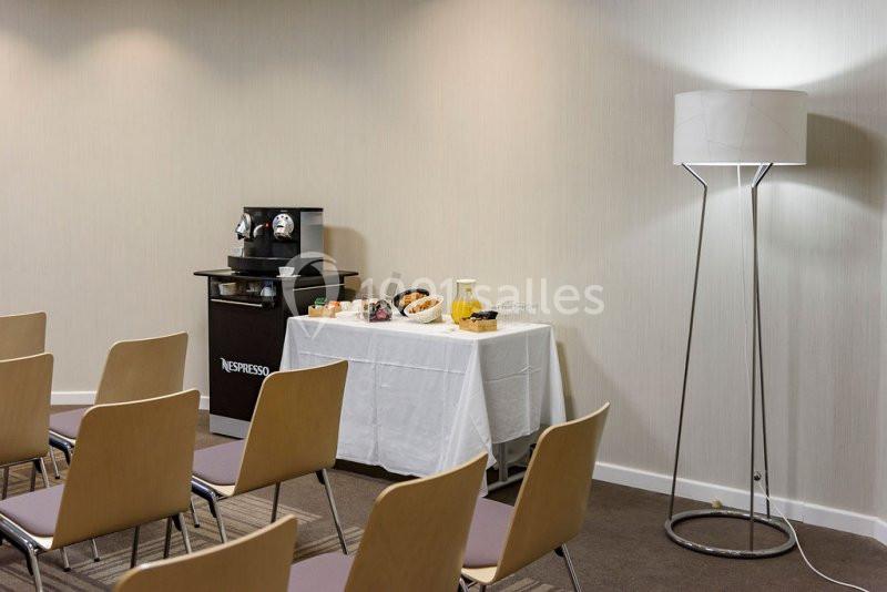 Table avec collation et machine à café dans une salle de réunion équipée de chaises et d'un lampadaire.