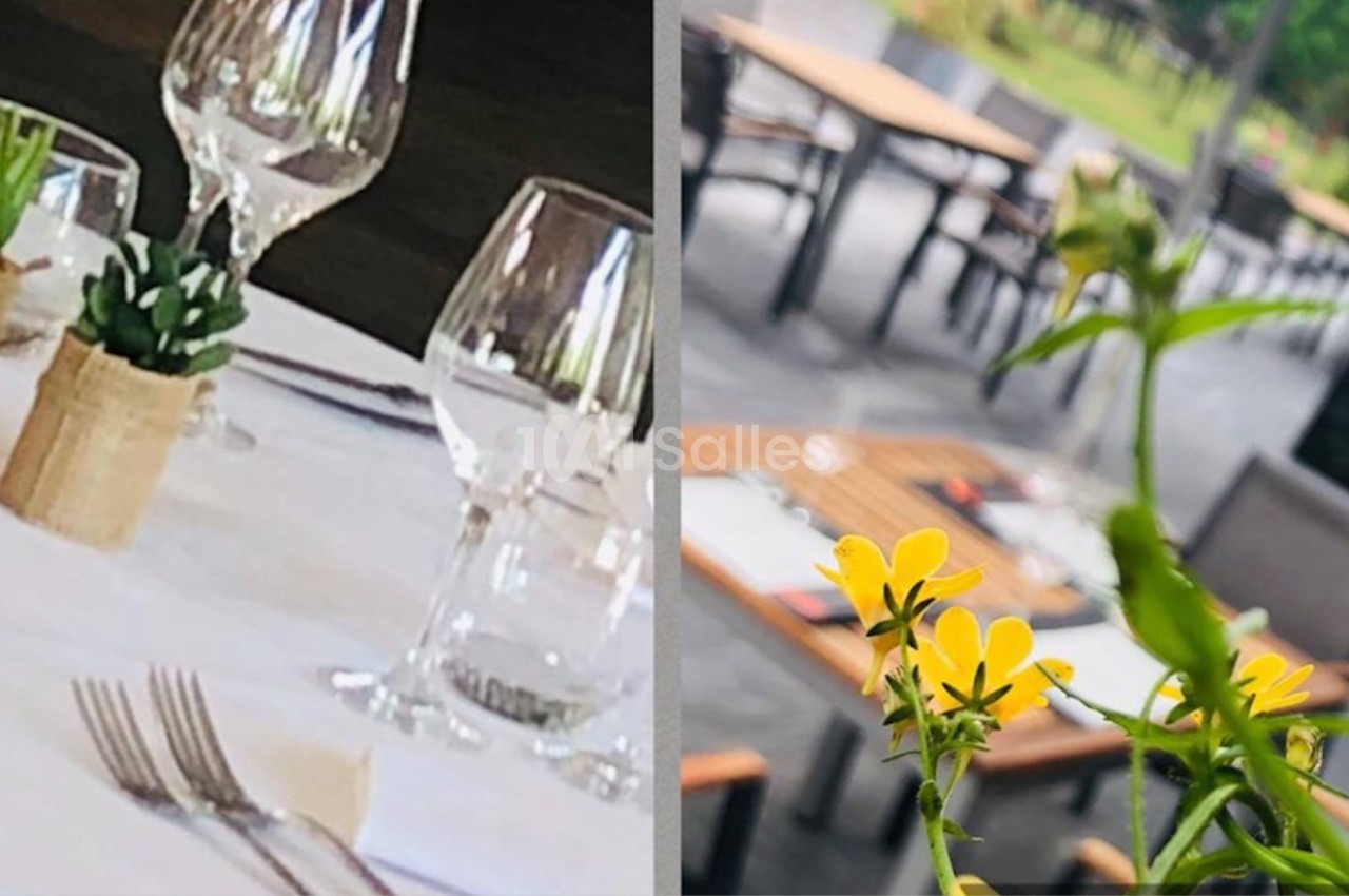 Table dressée avec verres et couverts à gauche, terrasse extérieure avec fleurs jaunes au premier plan à droite.