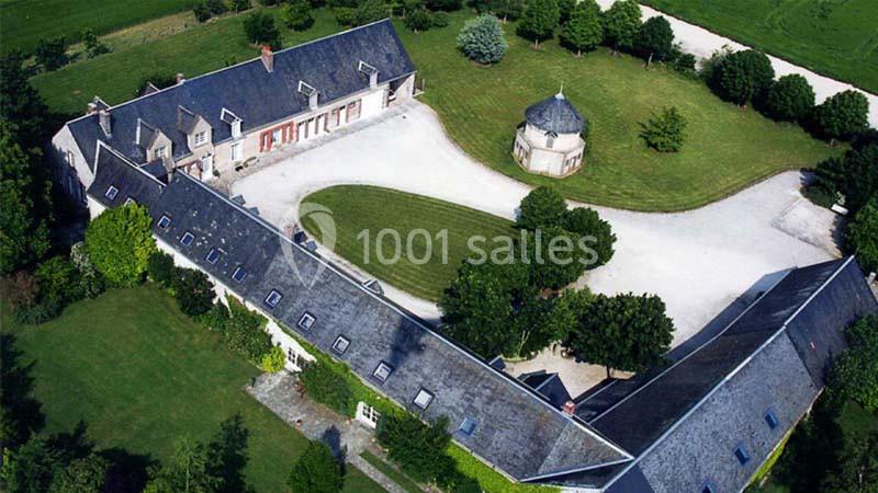 Vue aérienne d'un domaine avec bâtiments en forme de L, une cour centrale et un jardin arboré.