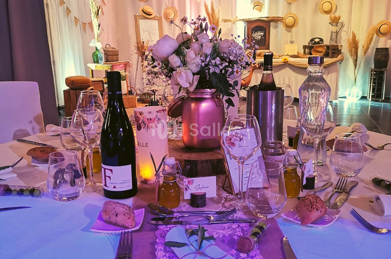 Table décorée pour un repas festif avec fleurs, bouteilles de vin, verres, pain et accessoires élégants.