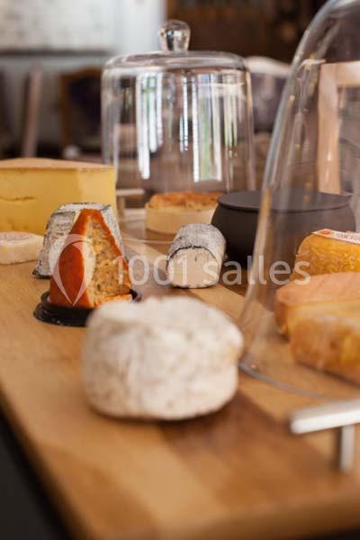 Plateau en bois avec une sélection variée de fromages sous cloches en verre dans un cadre intérieur.
