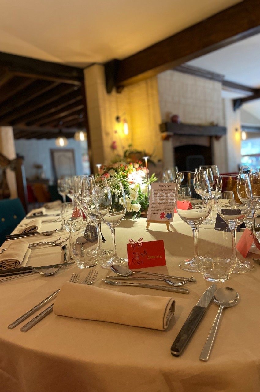 Table élégamment dressée avec des verres, couverts et décorations florales dans un restaurant à l'ambiance chaleureuse.