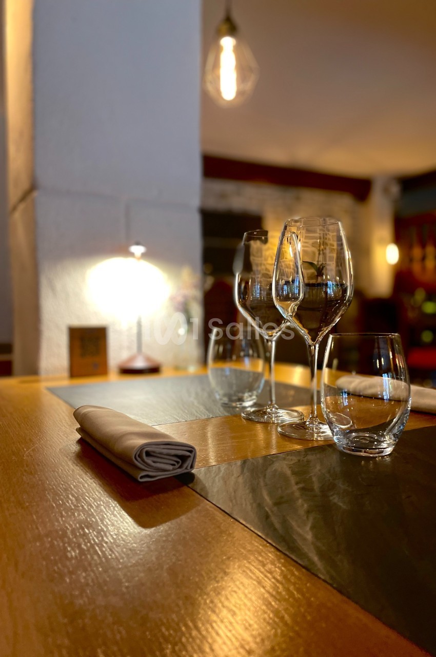 Table dressée avec des verres et des serviettes dans un restaurant à l'éclairage tamisé.