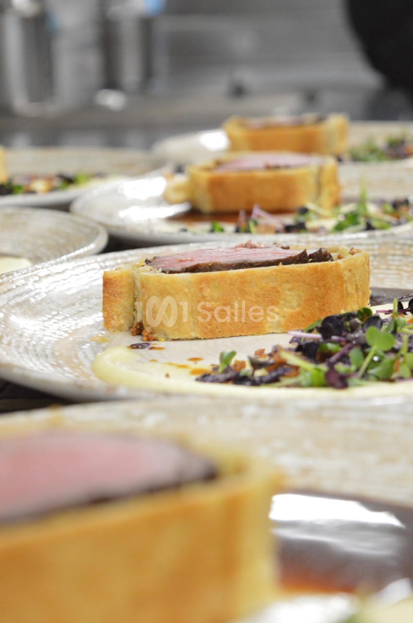 Tranche de bœuf Wellington servie sur une purée, accompagnée de jeunes pousses et d'une garniture croquante.