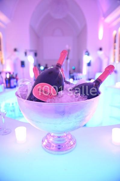 Un grand seau en métal rempli de glace contenant des bouteilles de champagne dans un décor lumineux et festif.