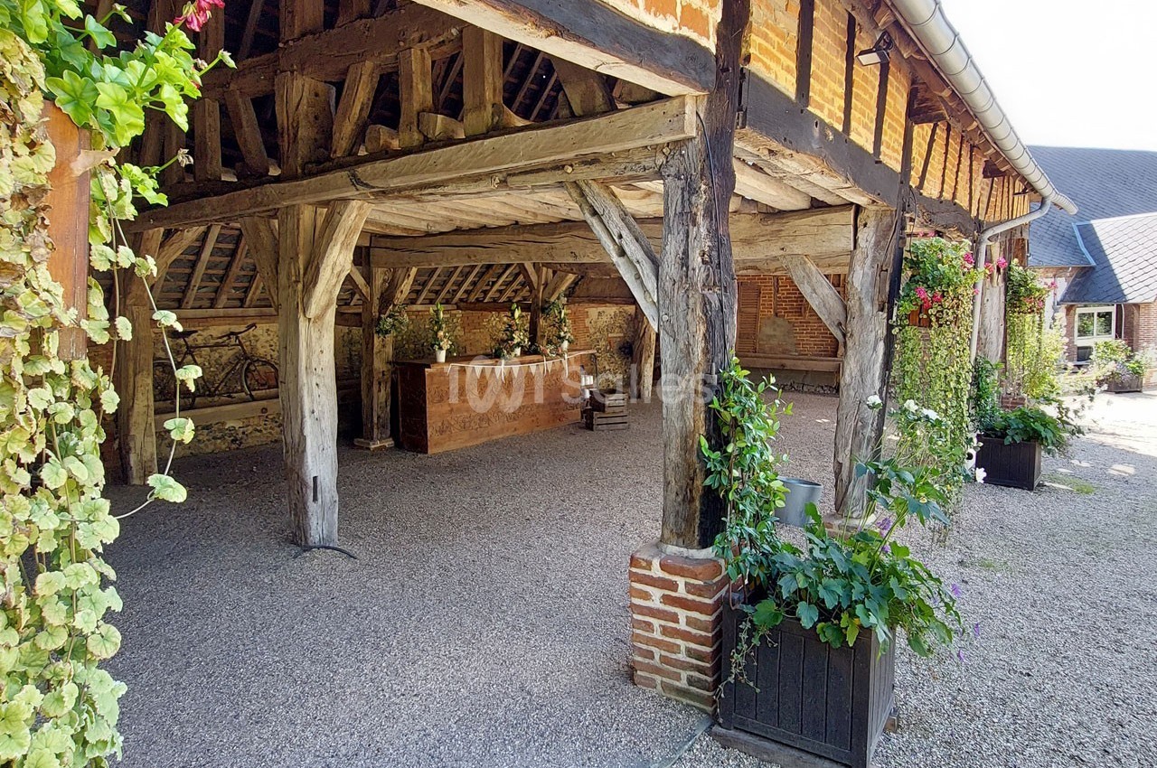 Charpente en bois apparente d'une grange ancienne avec des plantes décoratives et un comptoir en bois.