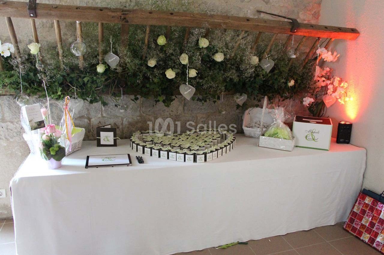 Table décorée avec des cadeaux, des fleurs et des friandises, disposée dans un cadre rustique avec un mur en pierre.