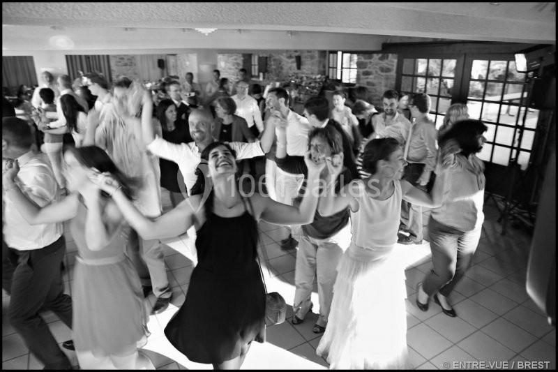 Groupe de personnes dansant joyeusement dans une salle lumineuse avec un sol carrelé.
