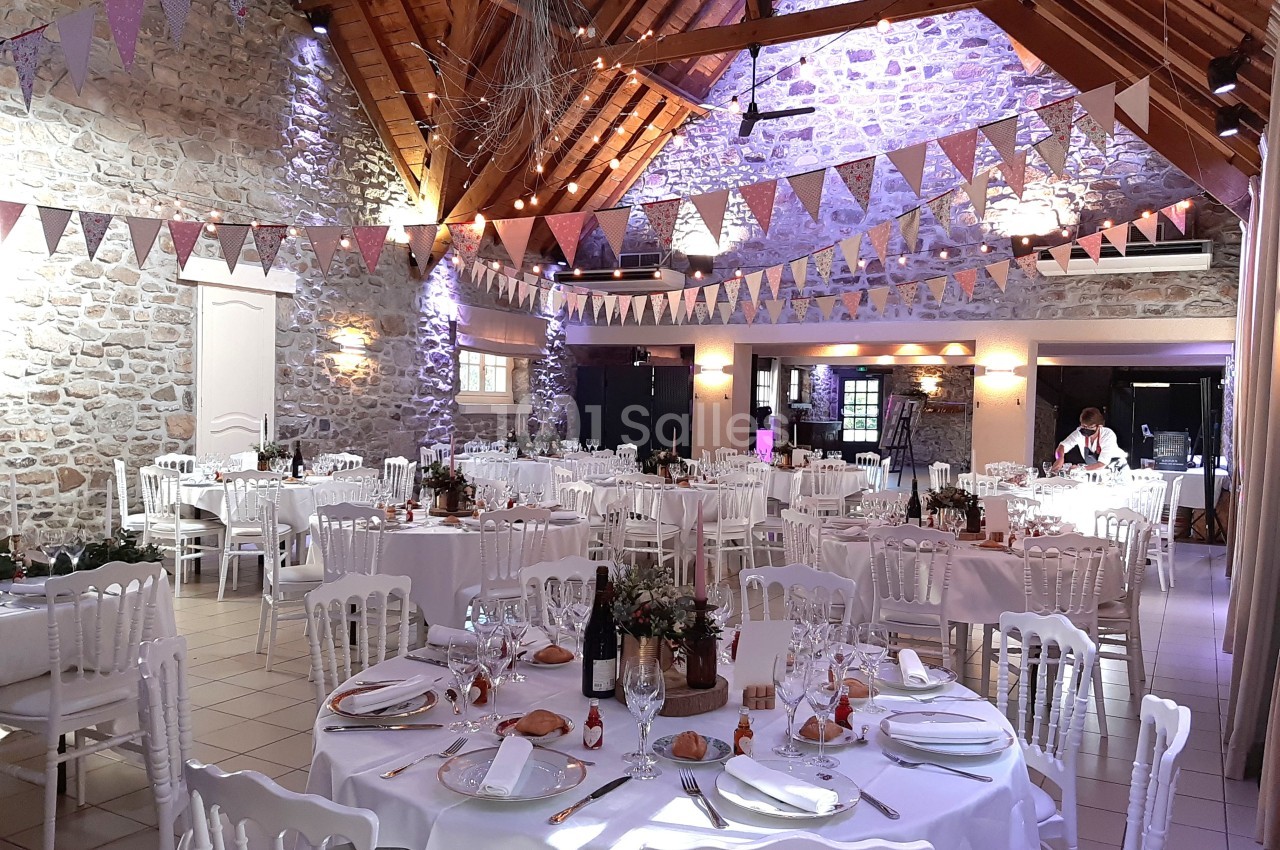 Salle de réception décorée avec des guirlandes et des tables dressées pour un événement festif.