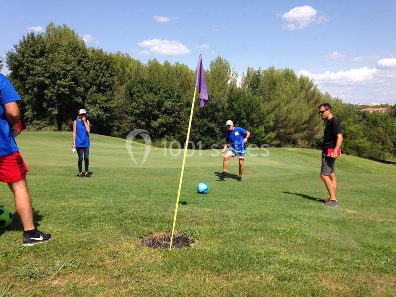 Parcours de golf en plein air avec drapeaux de trous, participants en tenue de sport dispersés sur le green.