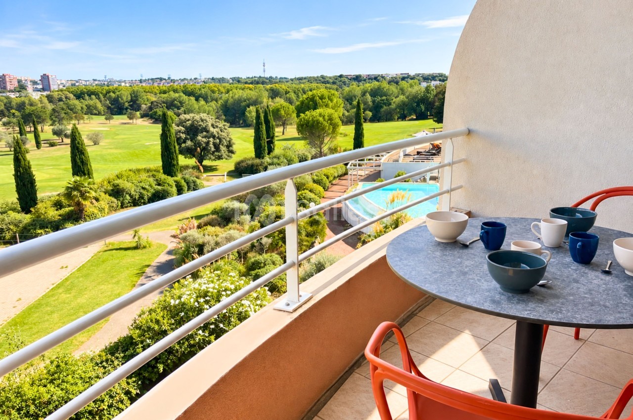 Terrasse avec table de petit-déjeuner, vue sur parc arborisé et piscine en contrebas.