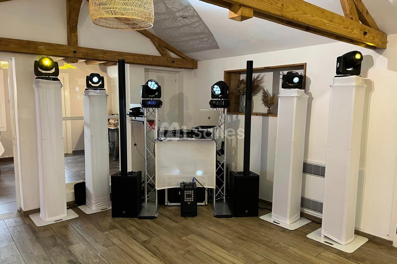 Équipement de sonorisation et éclairage installé dans une salle avec poutres apparentes et parquet en bois.