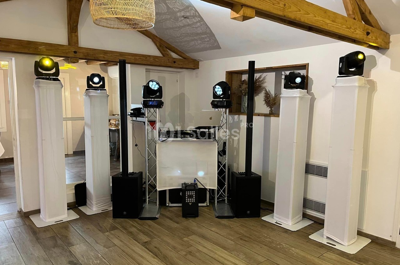Équipement de sonorisation et éclairage installé dans une salle avec poutres apparentes et parquet en bois.