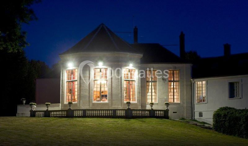 Façade éclairée d'un bâtiment ancien avec de grandes fenêtres, vue de nuit dans un environnement extérieur calme.