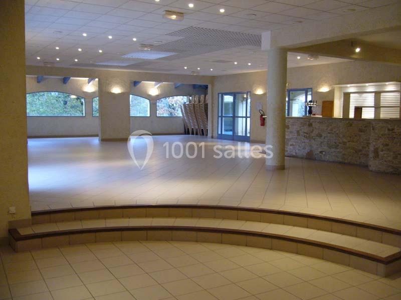Salle spacieuse et lumineuse avec carrelage clair, comptoir en pierre et chaises empilées près des fenêtres.