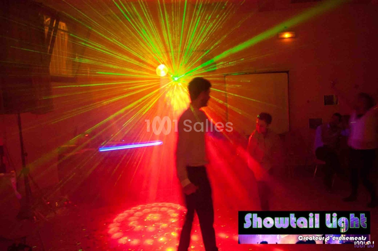 Un homme danse sous des lumières laser multicolores dans une salle sombre lors d'un événement festif.