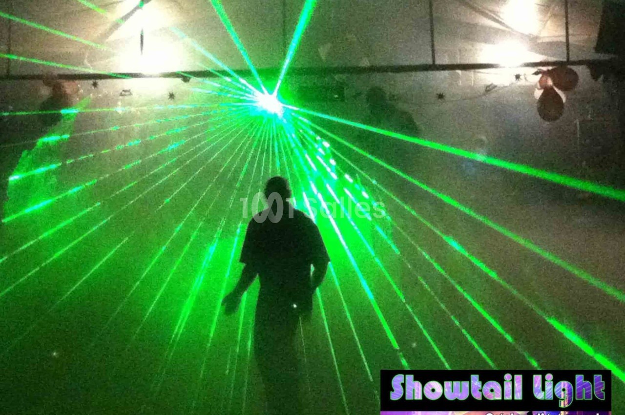Un homme debout dans une salle sombre éclairée par des faisceaux laser verts.