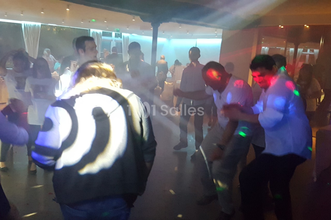 Des personnes dansent sous des lumières colorées dans une salle sombre, créant une ambiance festive.