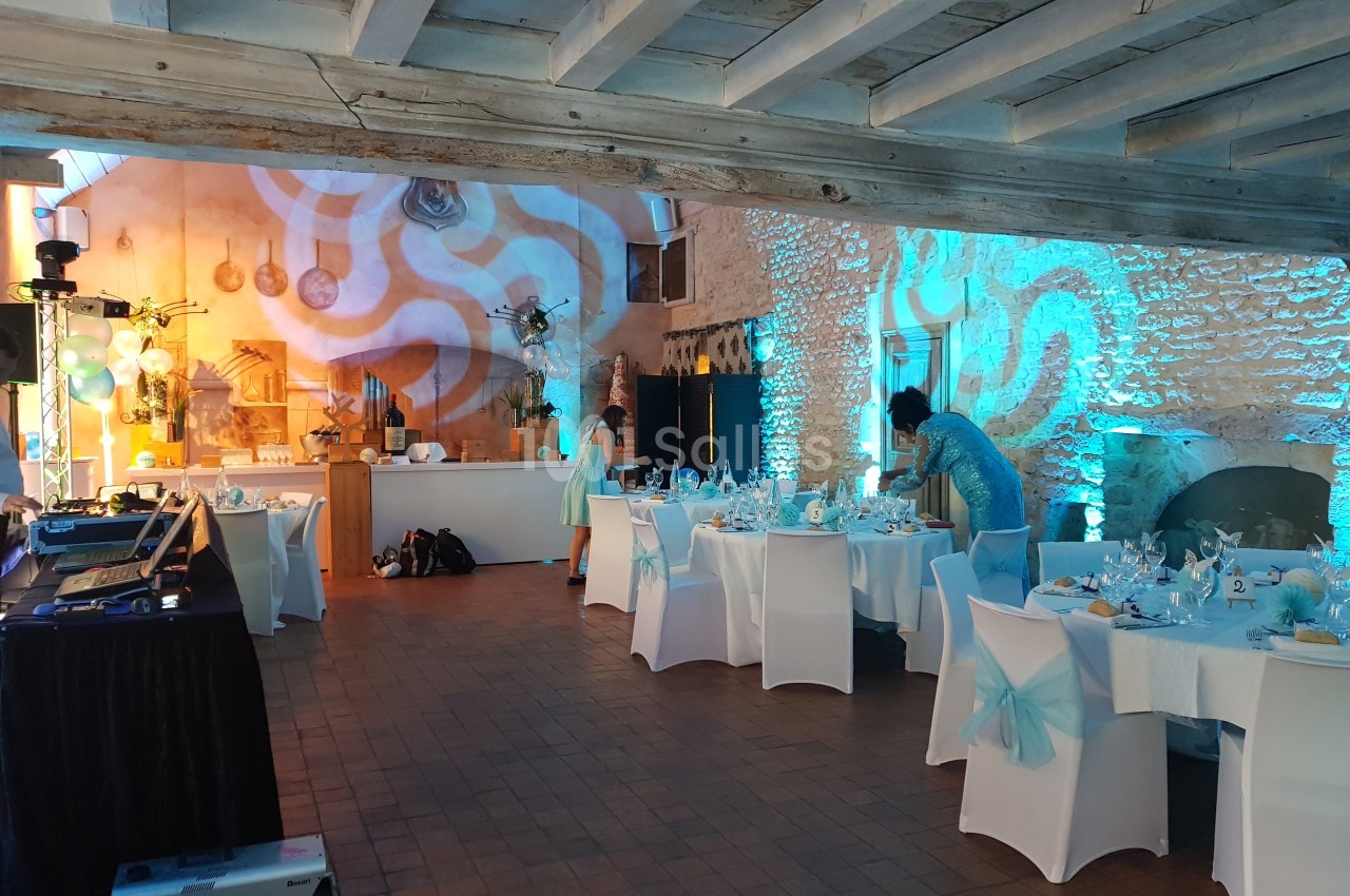 Salle de réception décorée avec des tables dressées, éclairage bleu et ambiance festive en préparation.