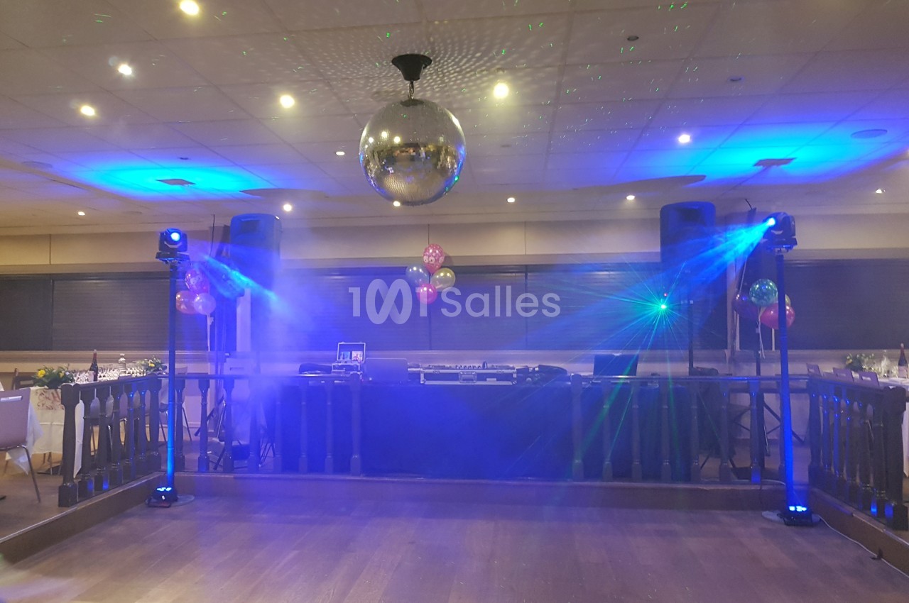 Salle de réception avec piste de danse, éclairages colorés, boule disco et équipement de sonorisation.